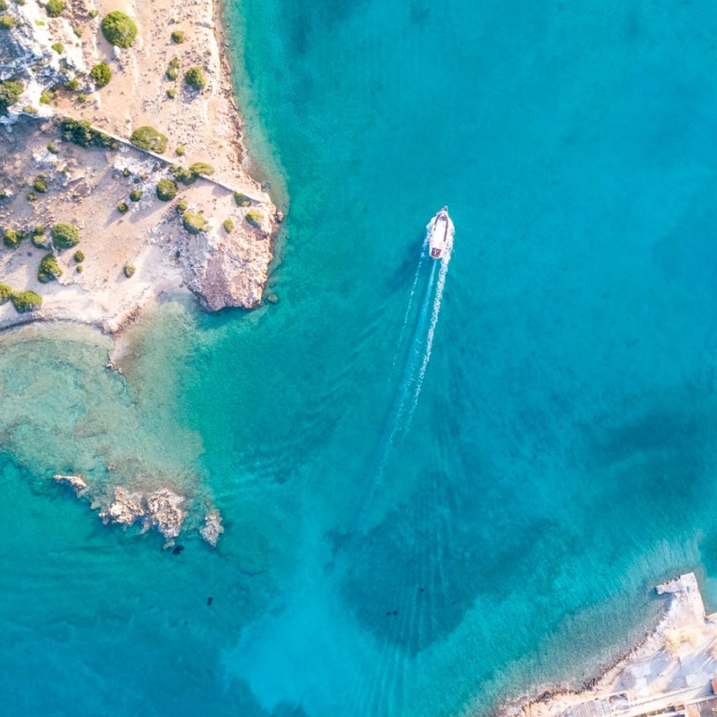 A sailboat anchored in a sheltered turquoise Greek cove